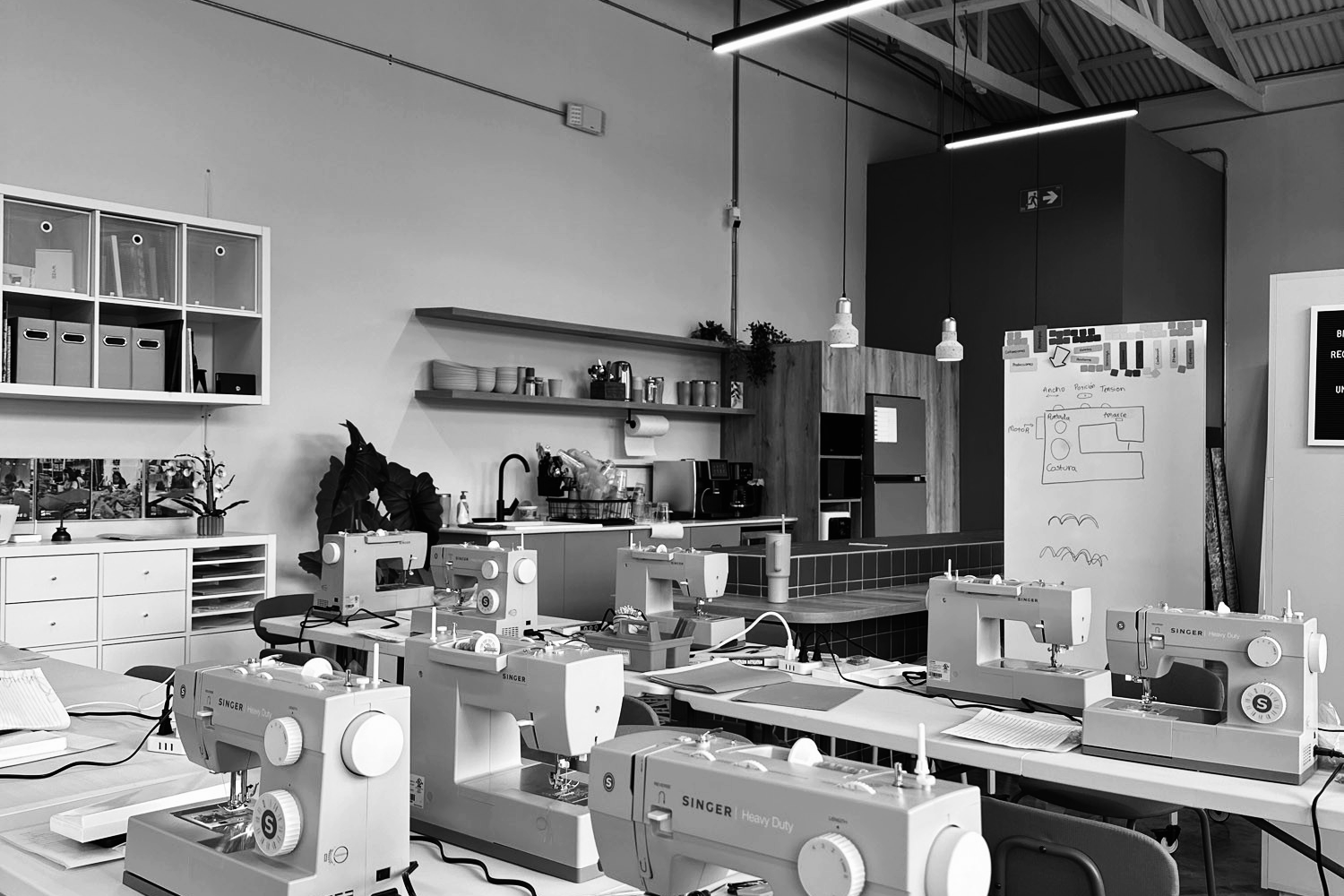 Vista en blanco y negro del aula equipada con máquinas de coser profesionales Singer para las clases de confección del programa Yo Aprendo de la Fundación Estudio TAC.