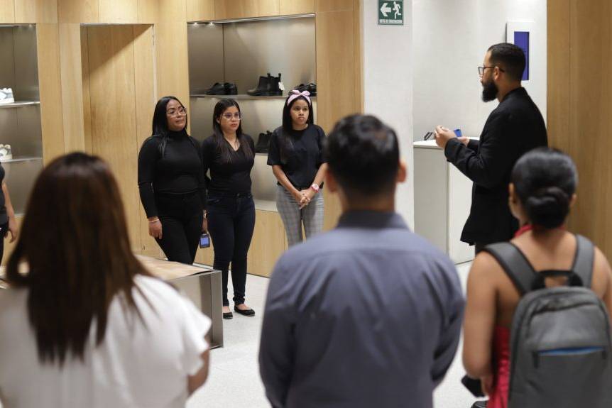 Un grupo de estudiantes del programa Yo Aprendo escucha la inducción de un facilitador durante una jornada práctica de retail en una tienda de calzado aliada.